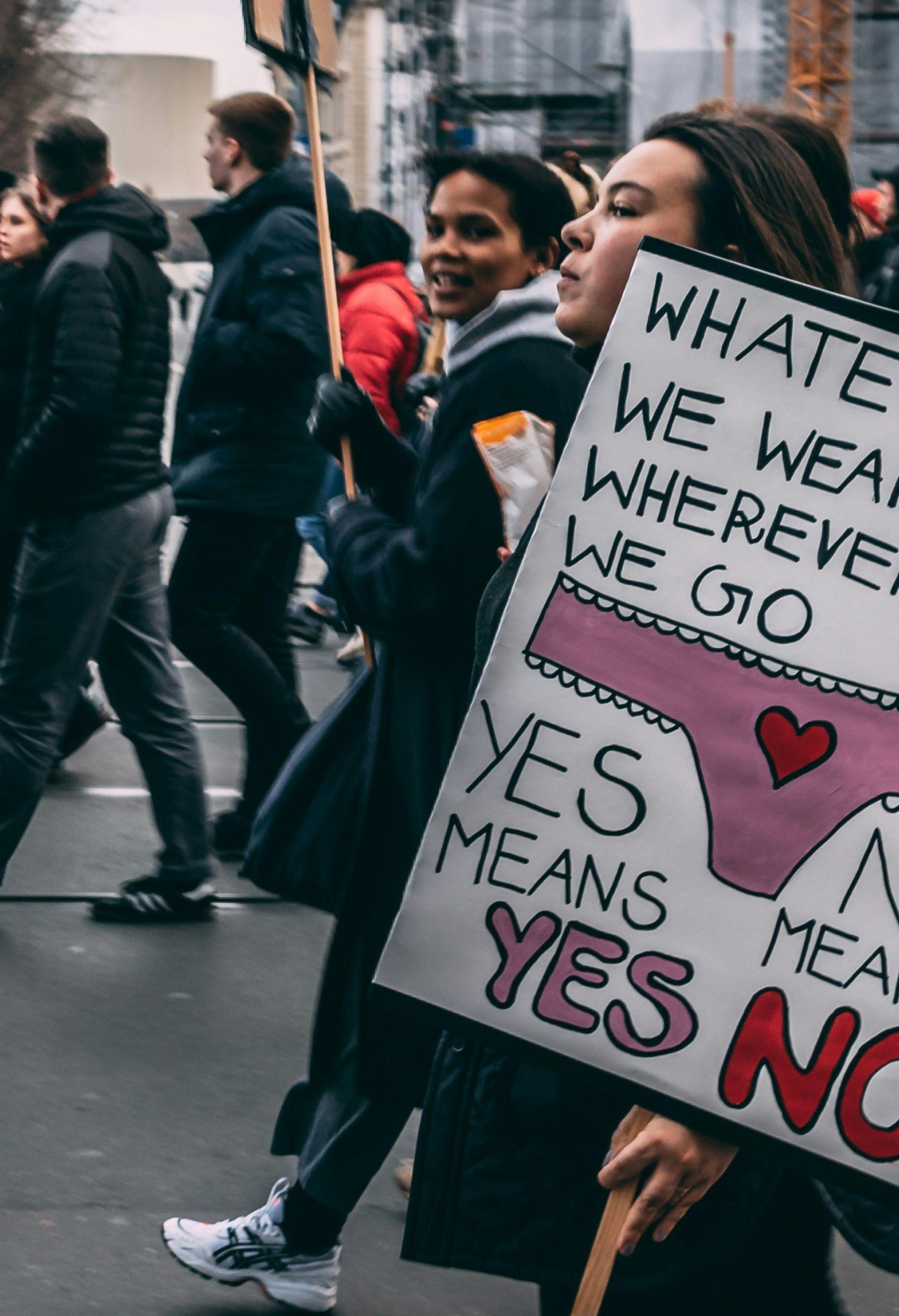 An image from Women's march in Berlin. 8th March 2020. A woman at the front holds a sign that reads "Whatever we wear, Wherever we go, Yes means yes, No means no."